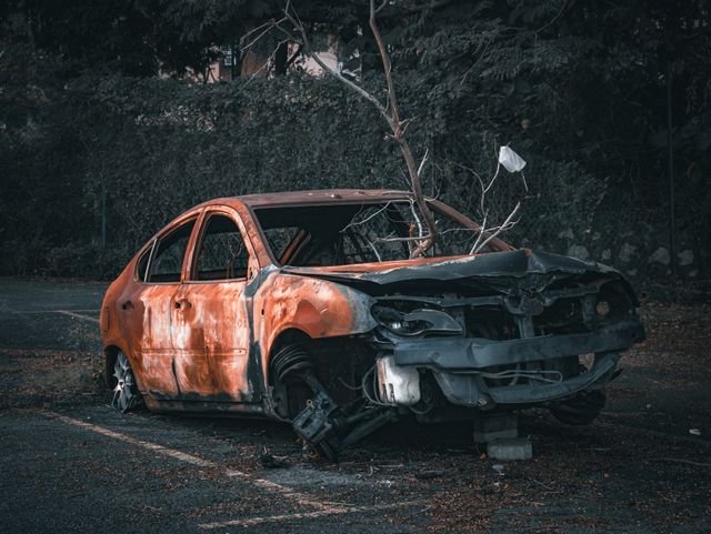 https://www.pexels.com/photo/abandoned-car-with-tree-stem-12950223/